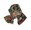 A lightweight square scarf with a vibrant, painterly floral print featuring pink, red, purple, green, and orange flowers on a dark background, styled in a loose knot on a plain white background.